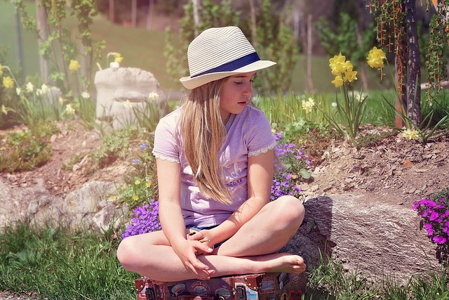 dívka sedící na kufru v zahradě